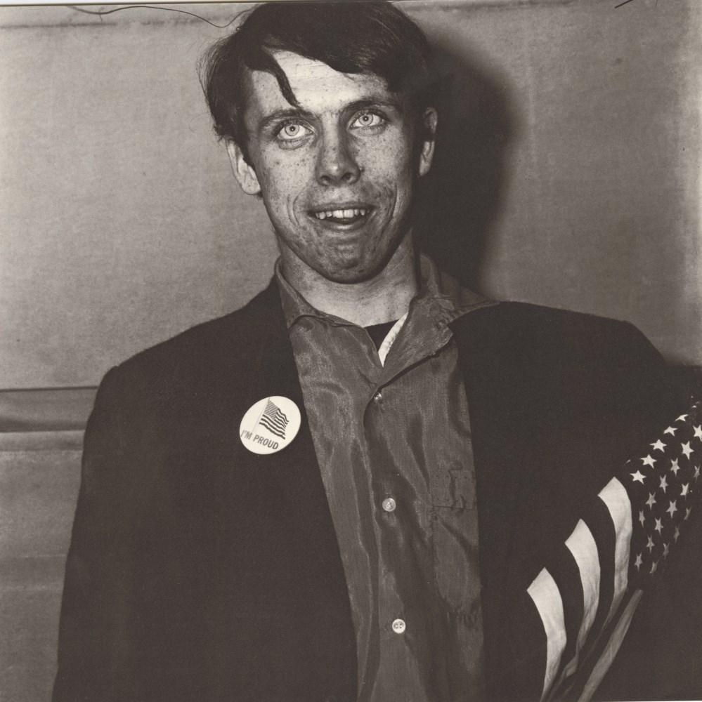 Lot #503: DIANE ARBUS - Patriotic Young Man with a Flag, N.Y.C - Original vintage photogravure